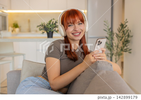 Young woman with headphones enjoys music from smartphone relax unwind breathing calm soft smile vibe 142899179
