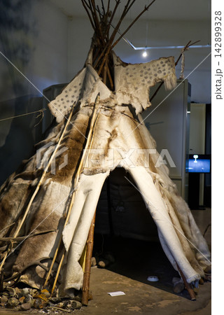 A museum exhibition model of a prehistoric dwelling, teepee, or hut constructed from wooden poles and animal hides on display at a museum in Dessau, Germany. The ancient shelter reconstruction is show A museum exhibition model of a prehistoric dwelling, teepee, or hut constructed from wooden poles and animal hides on display at a museum in Dessau, Germany. The ancient shelter reconstruction is show 142899328