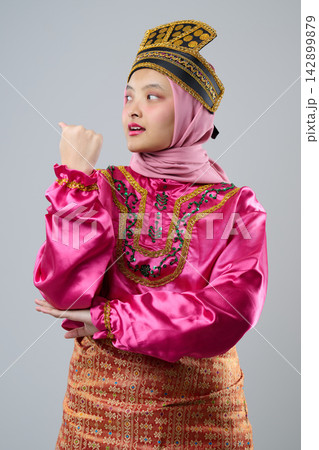 Young Indonesian Asian Woman In Pink Traditional Malay Costume And Hijab Wearing Ornate Headpiece Celebrating Cultural Heritage Young Indonesian Asian Woman In Pink Traditional Malay Costume And Hijab Wearing Ornate Headpiece Celebrating Cultural Heritage 142899879