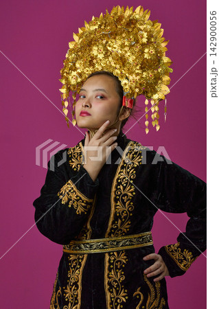 Portrait Of Young Indonesian Asian Woman Wearing Ornate Gold Traditional Headdress And Embroidered Black Costume Portrait Of Young Indonesian Asian Woman Wearing Ornate Gold Traditional Headdress And Embroidered Black Costume 142900056