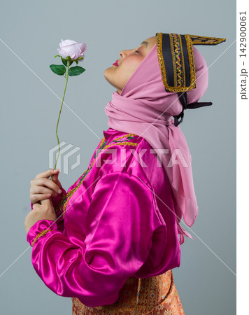 Profile Portrait of Indonesian Asian Woman in Pink Hijab and Traditional Headpiece Holding a Rose Profile Portrait of Indonesian Asian Woman in Pink Hijab and Traditional Headpiece Holding a Rose 142900061