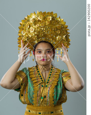 Portrait Of Indonesian Asian Woman Wearing Ornate Gold Headdress And Traditional Decorative Costume In Studio Portrait Of Indonesian Asian Woman Wearing Ornate Gold Headdress And Traditional Decorative Costume In Studio 142900200