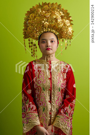 Young Indonesian Asian Girl Wearing Traditional Chinese Golden Headdress and Embroidered Red Ceremonial Costume Young Indonesian Asian Girl Wearing Traditional Chinese Golden Headdress and Embroidered Red Ceremonial Costume 142900214