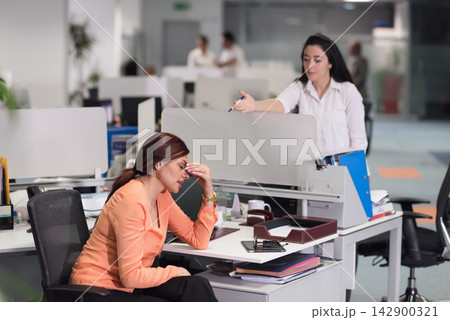 Middle Eastern colleagues in a modern office as a stressed employee receives feedback from a coworker 142900321