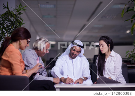 Middle Eastern business team in a modern open office meeting signing a contract and collaborating Middle Eastern business team in a modern open office meeting signing a contract and collaborating 142900398