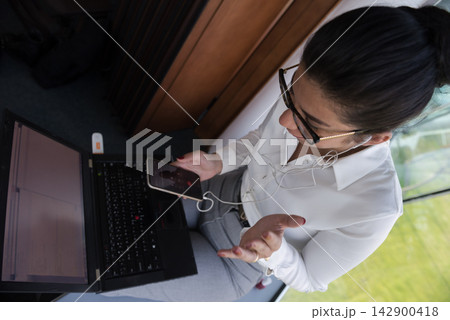 Middle Eastern businesswoman on a video call in a modern open office using laptop and smartphone Middle Eastern businesswoman on a video call in a modern open office using laptop and smartphone 142900418