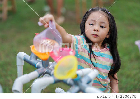 preschool child girl playing pouring water into pipe sensory play station in park preschool child girl playing pouring water into pipe sensory play station in park 142900579