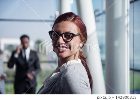Smiling professional woman in a corporate startup office during a busy business meeting Smiling professional woman in a corporate startup office during a busy business meeting 142900815