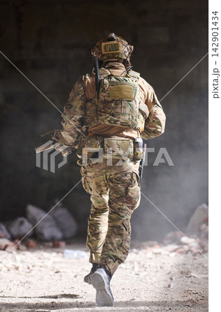 Soldier in Camouflage Tactical Gear Running Through Dusty Building During Urban Military Training Operation Soldier in Camouflage Tactical Gear Running Through Dusty Building During Urban Military Training Operation 142901434