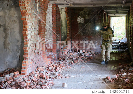 Soldier With Flashlight Clearing a Rubble-Filled Corridor in Abandoned Urban Ruins Tactical Operation 142901712