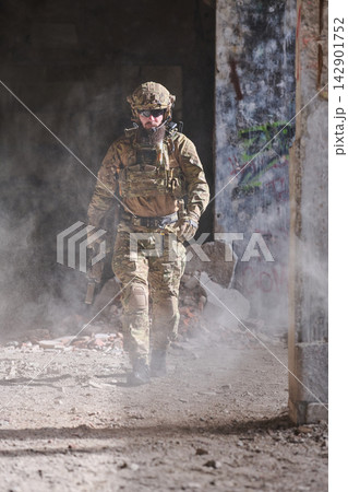 Armed Soldier In Tactical Gear Walking Through Dusty Urban Ruins During Military Operation 142901752