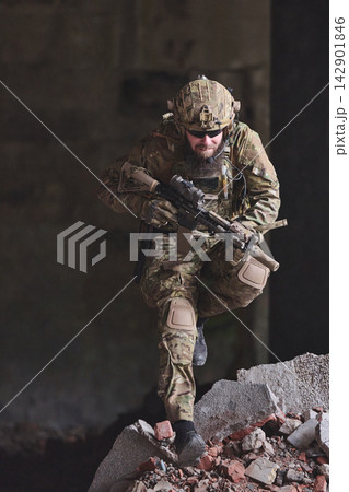 Soldier In Camouflage Tactical Gear Moving Through Urban Ruins With Rifle During Training Operation 142901846