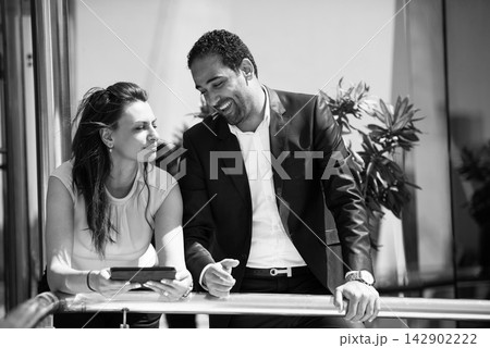 Business colleagues smiling and talking during a casual corporate meeting in a modern open office 142902222