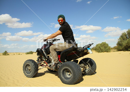 Young quad bike rider doing wheelie in desert 142902254