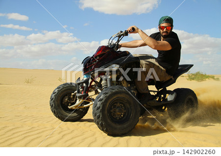 Young quad bike rider doing wheelie in desert 142902260