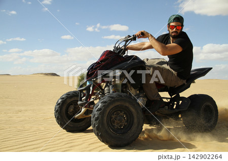 Young quad bike rider doing wheelie in desert 142902264