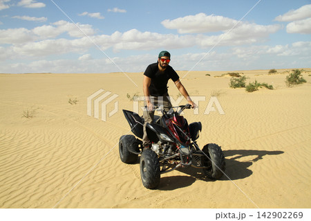 Young quad bike rider doing wheelie in desert 142902269