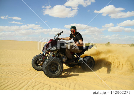 Young quad bike rider doing wheelie in desert Young quad bike rider doing wheelie in desert 142902275