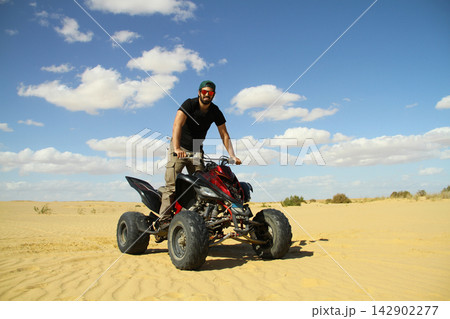 Young quad bike rider doing wheelie in desert 142902277