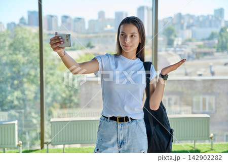 Young female student recording video blog on smartphone near window 142902282
