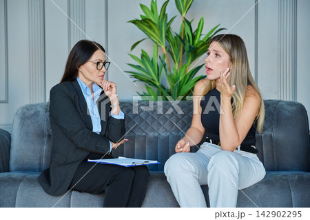 Emotional young woman gesturing during therapy session with psychologist 142902295