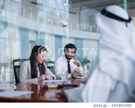 Middle Eastern professionals in a modern business meeting discussing strategy in a corporate boardroom Middle Eastern professionals in a modern business meeting discussing strategy in a corporate boardroom 142902300