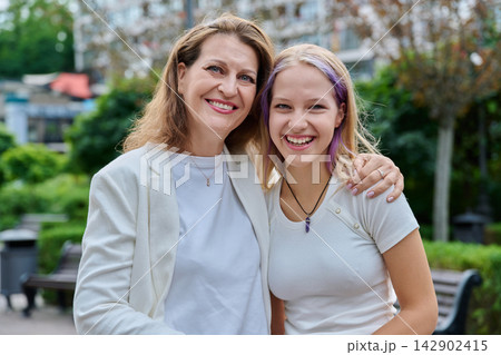 Happy mother and teenage daughter smiling outdoors in city park 142902415