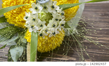 A bouquet of chrysanthemums and other flowers in light-colored wrapping paper 142902437