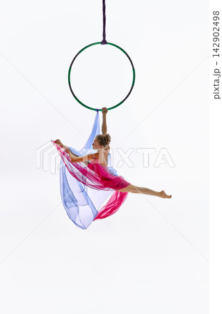 Teen gymnast posing below green aerial ring 142902498