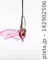 Teen girl suspended from green aerial hoop with pink fabric 142902506