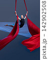 Teen aerialist opening arms between flowing silks 142902508