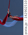 Teen girl stretching horizontally above red fabric 142902510