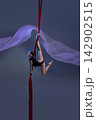 Teen girl holding dynamic pose above red silks 142902515