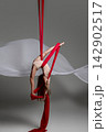 Teen girl inverted on red aerial silks 142902517