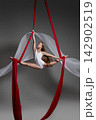 Teen girl performing split on red aerial silks 142902519