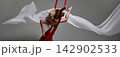 Young gymnast curving around red aerial silks 142902533