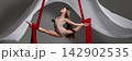 Young aerialist holding wide split on red silks 142902535