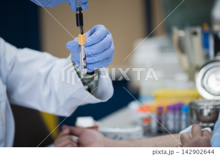 Lab technician drawing blood sample for medical testing in clinical laboratory by healthcare staff 142902644