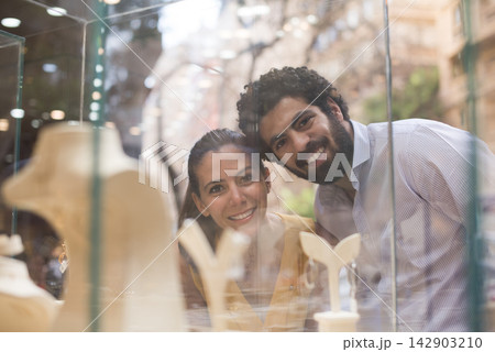 Middle Eastern couple smiling while shopping for a wedding ring with friends and family at a jewelry store 142903210