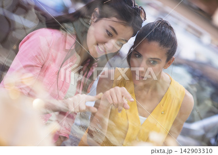 Couple shopping for a wedding ring with friends pointing at a jewelry display 142903310