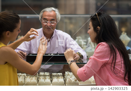 Middle Eastern couple shopping for a wedding ring with friends and family at a jewelry store 142903325