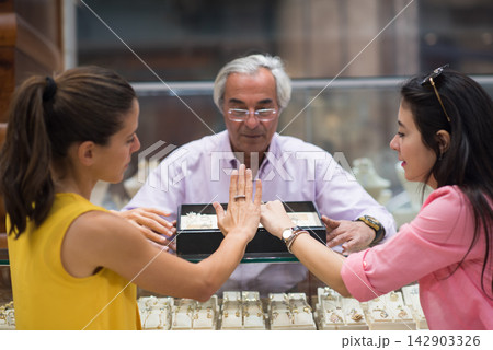 Middle Eastern couple choosing a wedding ring with friends and family at a jewelry store 142903326