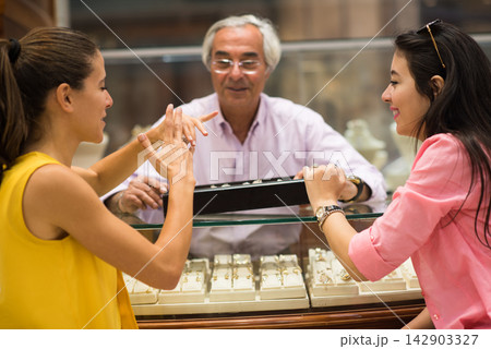 Middle Eastern couple shopping for a wedding ring with friends and family at a jewelry store 142903327