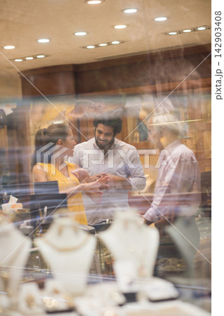 Middle Eastern couple shopping for a wedding ring with friends and family in a jewelry store Middle Eastern couple shopping for a wedding ring with friends and family in a jewelry store 142903408