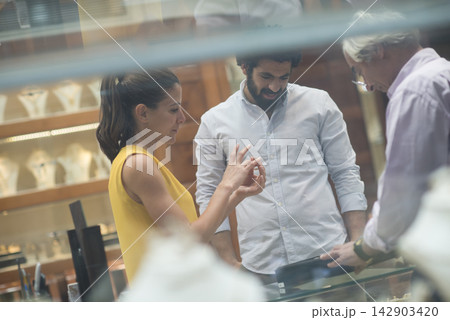 Couple choosing a wedding ring together with friends and family at a jewelry store Couple choosing a wedding ring together with friends and family at a jewelry store 142903420