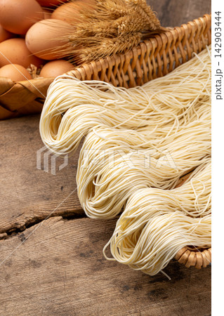 fresh Handmade Raw Wheat Noodles Resting on Wooden Surface 142903444