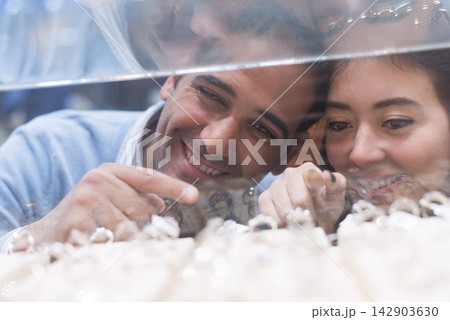 Couple buying wedding rings with friends and family while smiling and choosing a ring at a jewelry store 142903630