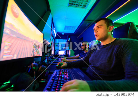 Focused Gamers Playing Multiplayer PC Shooter in Neon-Lit Esports Gaming Room 142903974