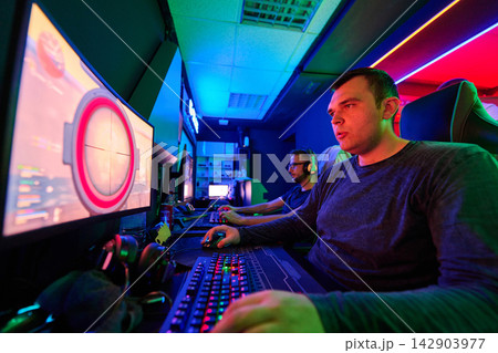 Focused Gamers Playing Competitive PC Games in Neon-Lit Esports Gaming Room With Headsets 142903977