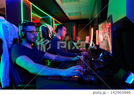 Competitive Gamers Playing Multiplayer PC Games In Neon-Lit Esports Gaming Arena With Headsets Competitive Gamers Playing Multiplayer PC Games In Neon-Lit Esports Gaming Arena With Headsets 142903990